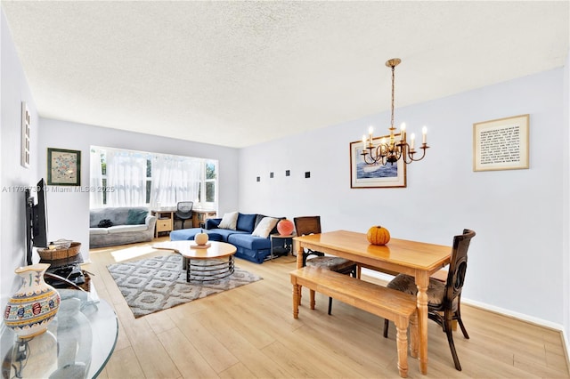 living area featuring light wood-style flooring, baseboards, and a textured ceiling