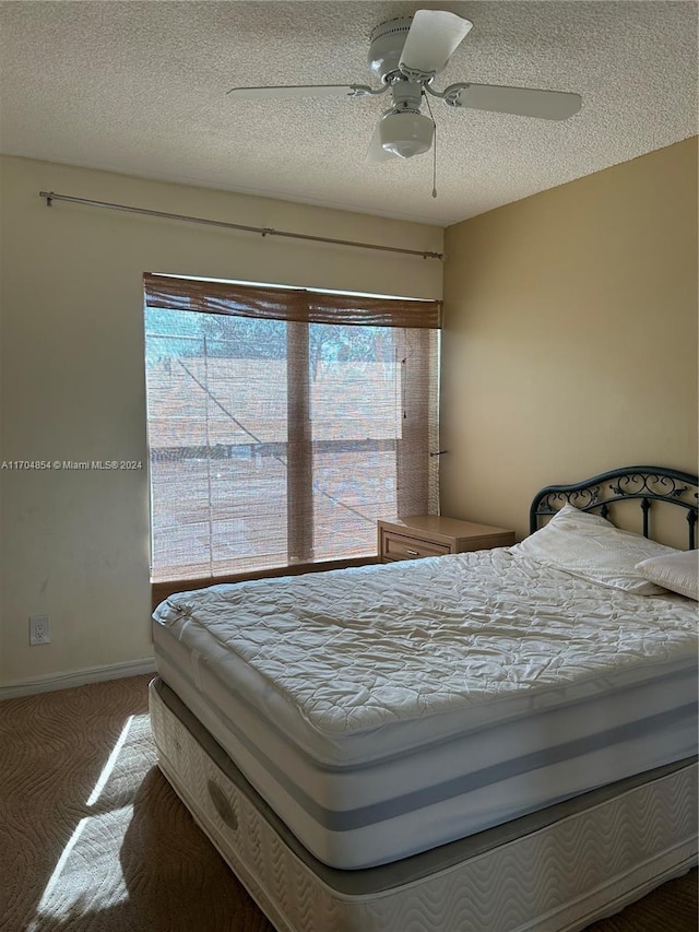 carpeted bedroom featuring ceiling fan, a textured ceiling, and multiple windows