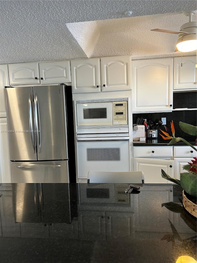 kitchen featuring white cabinetry, white appliances, and a textured ceiling