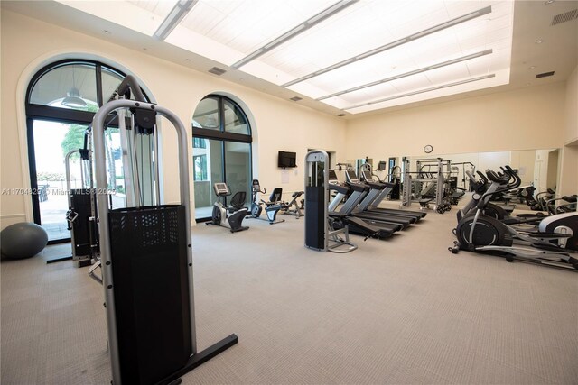 workout area with light colored carpet and a high ceiling