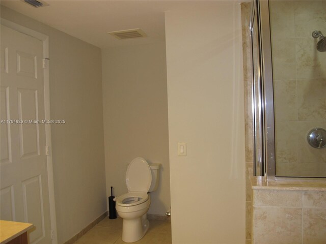 bathroom featuring tiled shower, tile patterned flooring, and toilet