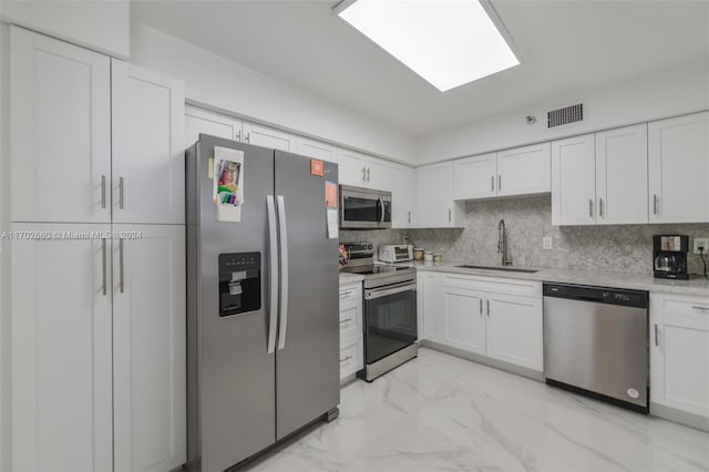 kitchen featuring decorative backsplash, appliances with stainless steel finishes, white cabinetry, and sink