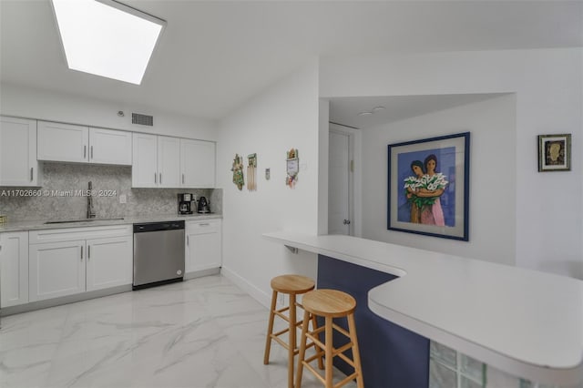 kitchen with stainless steel dishwasher, backsplash, white cabinets, and sink