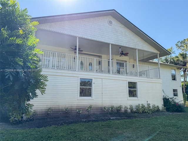 view of home's exterior with a balcony, ceiling fan, and a lawn