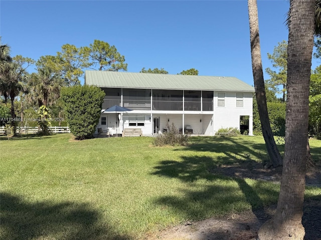 rear view of property featuring a sunroom and a lawn