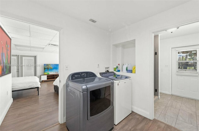 clothes washing area featuring washing machine and clothes dryer and light wood-type flooring