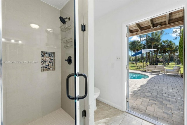 bathroom with tile patterned floors, toilet, and a shower with door