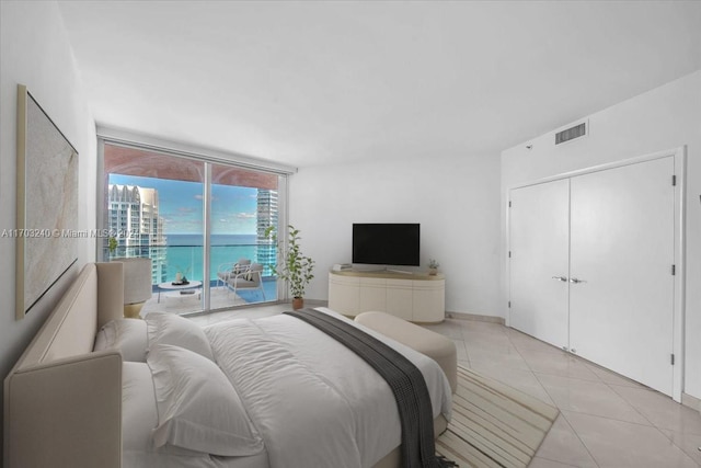 bedroom with access to exterior, light tile patterned floors, and a closet