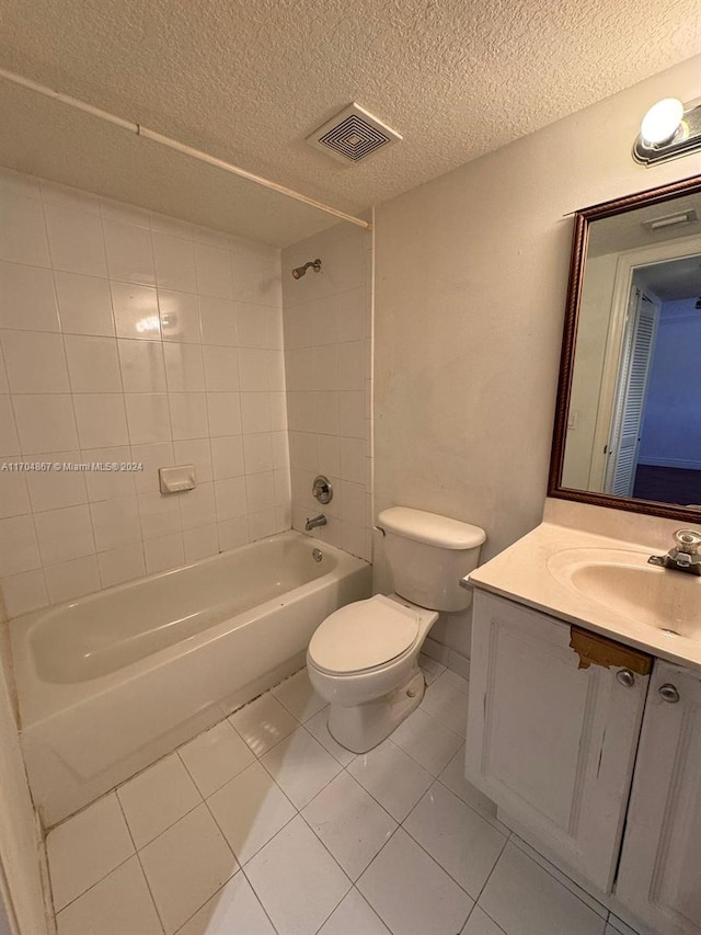 full bathroom with vanity, tile patterned floors, tiled shower / bath, toilet, and a textured ceiling