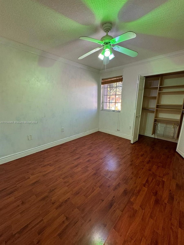 unfurnished bedroom featuring dark wood-type flooring, ceiling fan, ornamental molding, a textured ceiling, and a closet