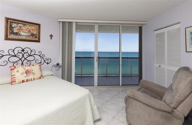 bedroom featuring access to exterior, expansive windows, a water view, and a closet