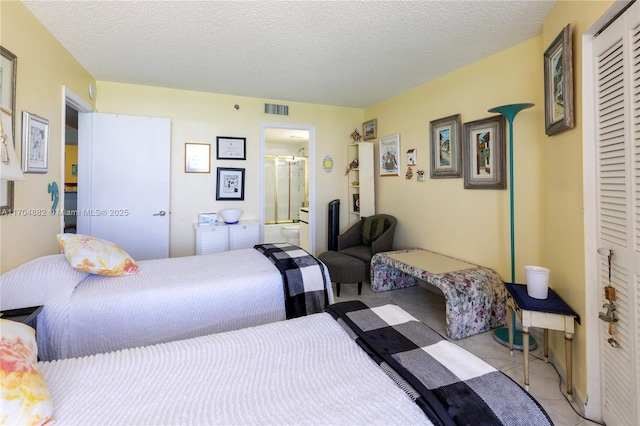 bedroom with light tile patterned floors, a textured ceiling, connected bathroom, and a closet