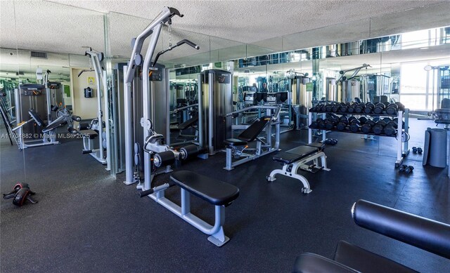 gym with floor to ceiling windows and a textured ceiling