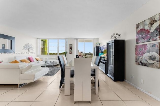 dining area with light tile patterned floors, floor to ceiling windows, and baseboards