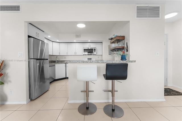 kitchen featuring white cabinets, stainless steel appliances, visible vents, and a peninsula