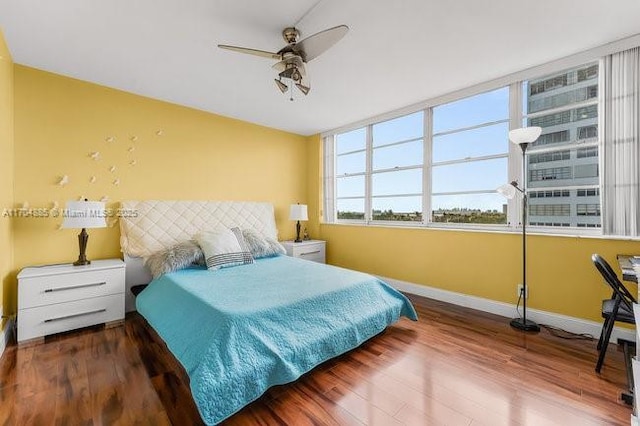 bedroom with wood finished floors, a ceiling fan, and baseboards