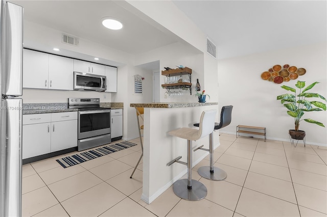 kitchen with appliances with stainless steel finishes, a breakfast bar area, a peninsula, and visible vents