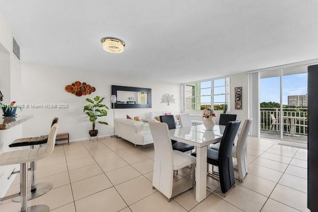 dining area featuring light tile patterned floors, visible vents, and floor to ceiling windows