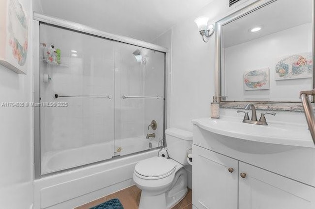 full bath with wood finished floors, shower / bath combination with glass door, vanity, and toilet