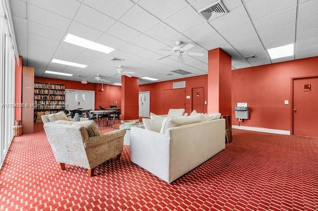 carpeted living room with a ceiling fan, a paneled ceiling, visible vents, and baseboards