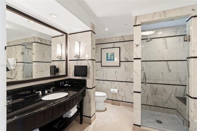 bathroom with vanity, toilet, an enclosed shower, and tile walls