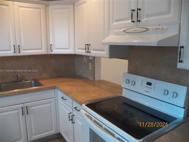 kitchen featuring white range with electric cooktop, decorative backsplash, white cabinets, and sink