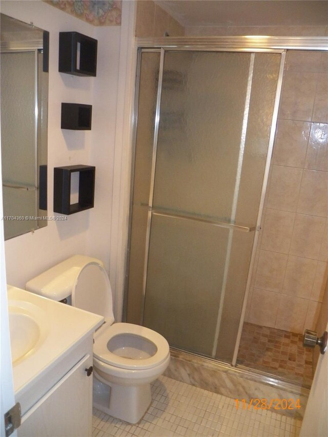 bathroom featuring tile patterned flooring, vanity, toilet, and walk in shower