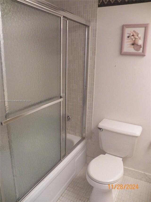 bathroom featuring tile patterned floors, enclosed tub / shower combo, and toilet