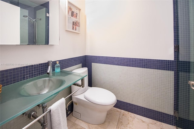 bathroom featuring toilet, sink, tile walls, and tiled shower