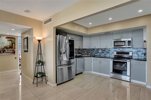 kitchen with backsplash, gray cabinets, and stainless steel appliances