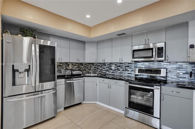 kitchen with tasteful backsplash, gray cabinetry, sink, and appliances with stainless steel finishes