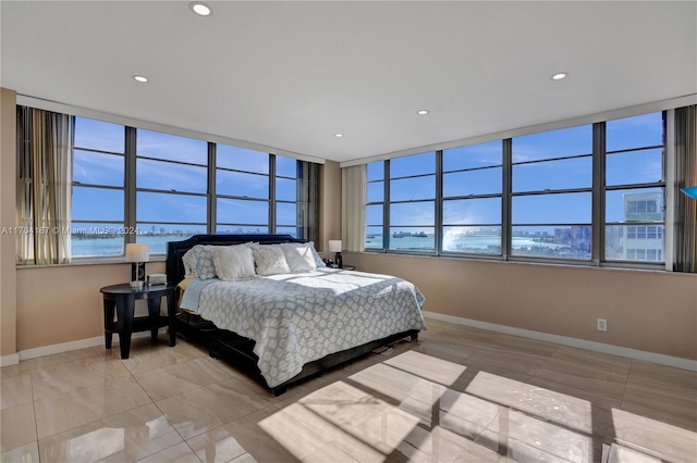 bedroom with multiple windows, a water view, and light tile patterned floors