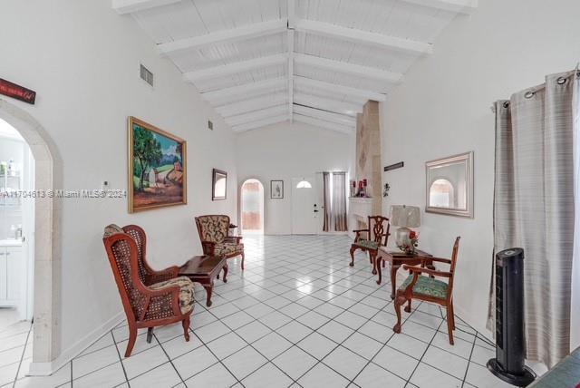 interior space with beamed ceiling, light tile patterned floors, wood ceiling, and high vaulted ceiling