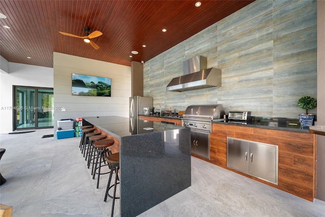 view of patio / terrace featuring grilling area, ceiling fan, an outdoor wet bar, and exterior kitchen