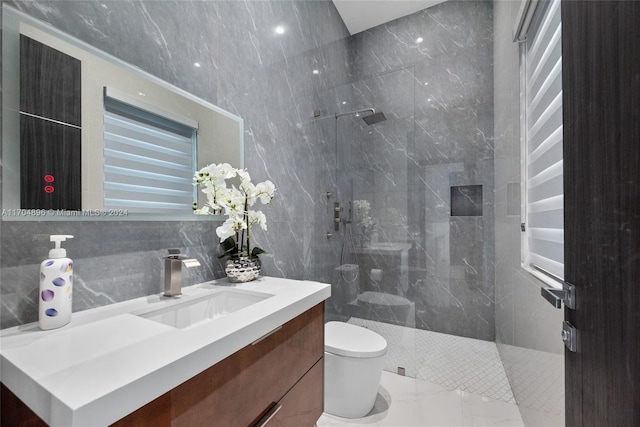 bathroom featuring a tile shower, vanity, toilet, and tile walls