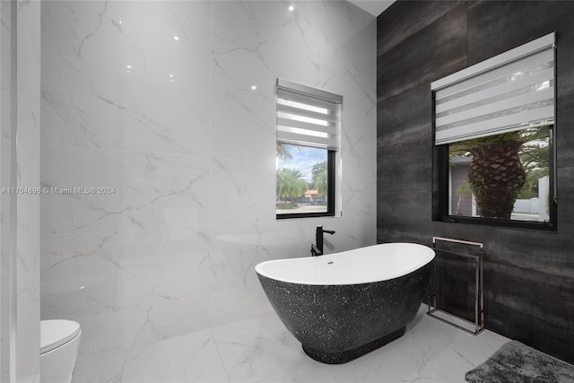 bathroom with a tub to relax in, toilet, and tile walls