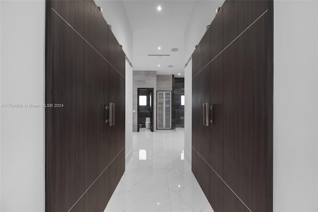 corridor featuring a barn door and tile walls