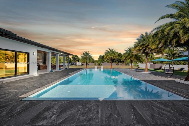 pool at dusk featuring a patio area