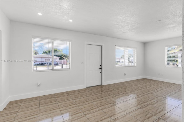 empty room featuring a healthy amount of sunlight and a textured ceiling