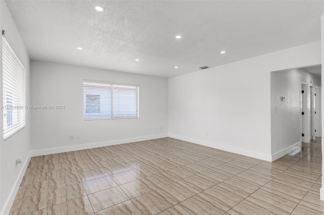 unfurnished room with a textured ceiling and plenty of natural light