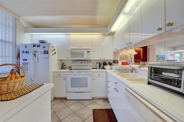 kitchen featuring a textured ceiling, white appliances, sink, white cabinetry, and light tile patterned flooring