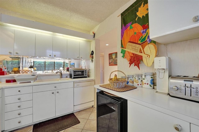 kitchen with white dishwasher, white cabinets, wine cooler, light tile patterned floors, and a textured ceiling