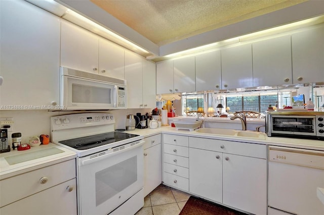 kitchen featuring a textured ceiling, white appliances, sink, light tile patterned floors, and white cabinets