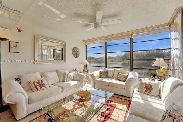 living room with ceiling fan, a water view, and a textured ceiling