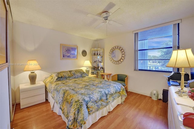 bedroom featuring ceiling fan, light hardwood / wood-style floors, and a textured ceiling