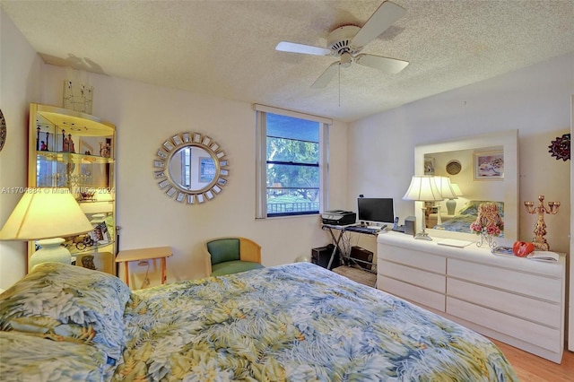 bedroom with ceiling fan, light hardwood / wood-style flooring, and a textured ceiling