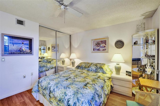 bedroom with ceiling fan, a closet, wood-type flooring, and a textured ceiling