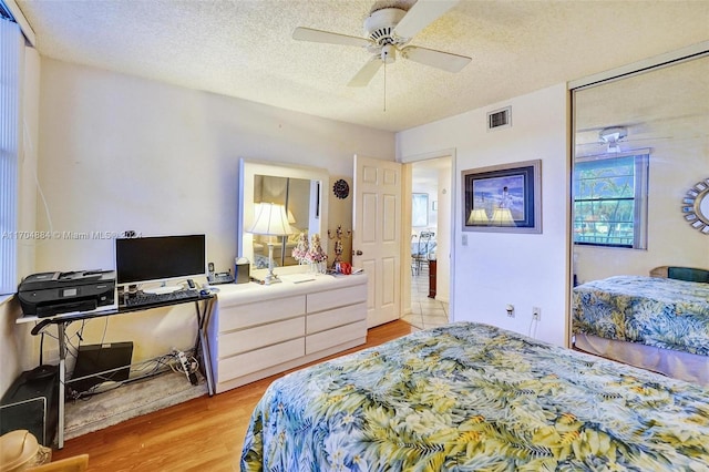 bedroom with a textured ceiling, light hardwood / wood-style floors, and ceiling fan