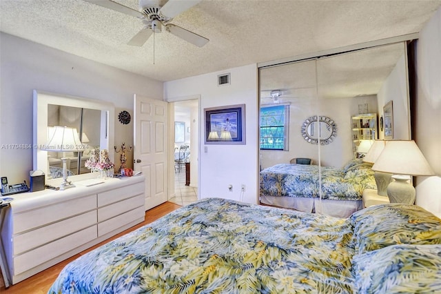 bedroom featuring ceiling fan, a closet, a textured ceiling, and light hardwood / wood-style flooring