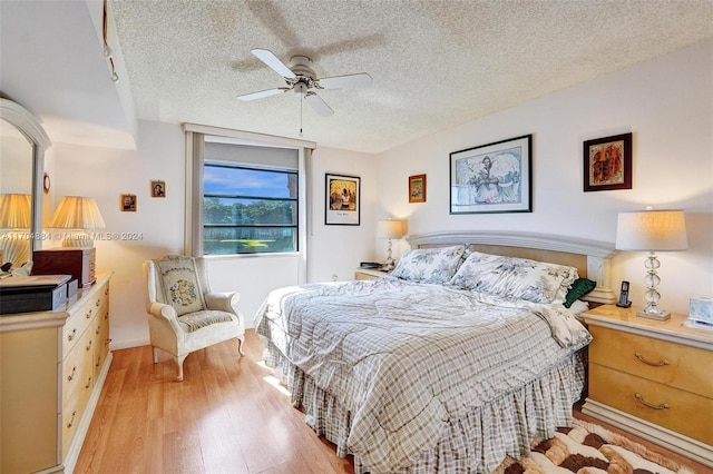 bedroom with ceiling fan, light hardwood / wood-style floors, and a textured ceiling